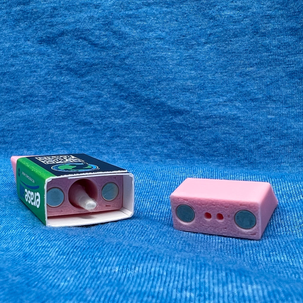 The eraser scent work hide shown opened.  From this angle you can see the magnets used to hold the hide closed as well as the chamber for adding odor.  A Q-tip head is inside the chamber demonstrating size. 